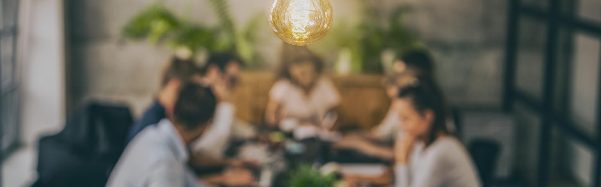 Photo of light bulb above a team in discussion